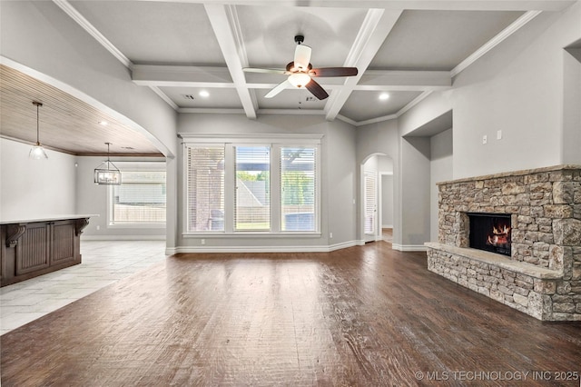 2236 W Charlotte St, Broken Arrow, OK 74011 - unfurnished living room featuring a fireplace, beam ceiling, arched walkways, ceiling fan, and baseboards