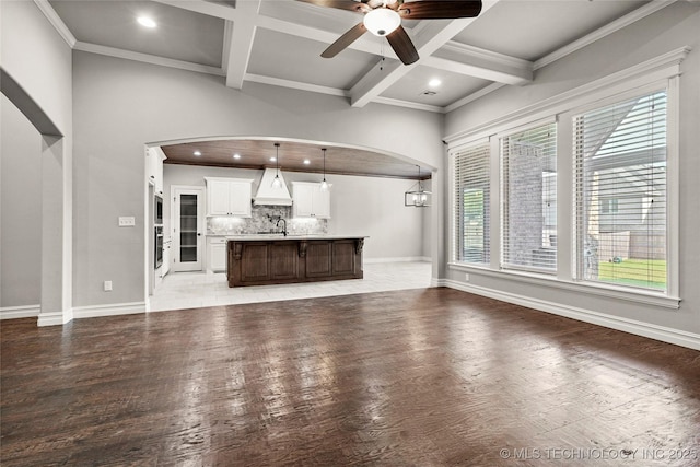 2236 W Charlotte St, Broken Arrow, OK 74011 - unfurnished living room featuring arched walkways, light wood-style flooring, beam ceiling, recessed lighting, and coffered ceiling