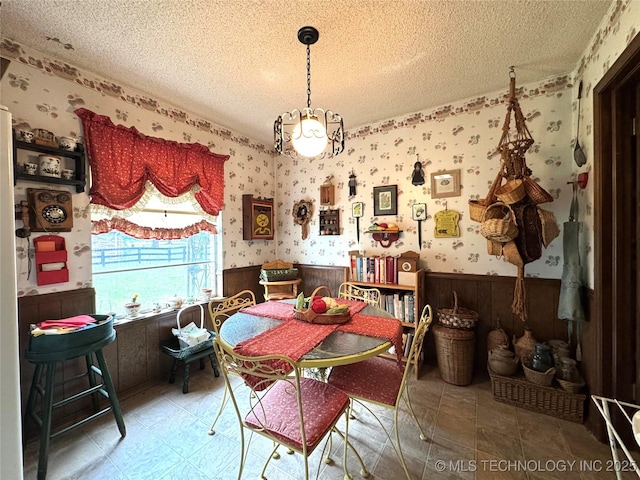 7122 S Shelby Ln, Broken Arrow, OK 74014 - dining space featuring wainscoting, a textured ceiling, wallpapered walls, and wood walls