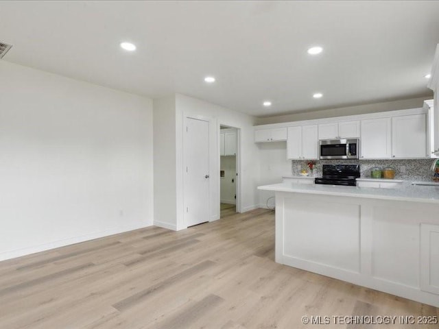 817 N Ivy St, Jenks, OK 74037 - kitchen with stainless steel microwave, electric range, light countertops, white cabinets, and backsplash