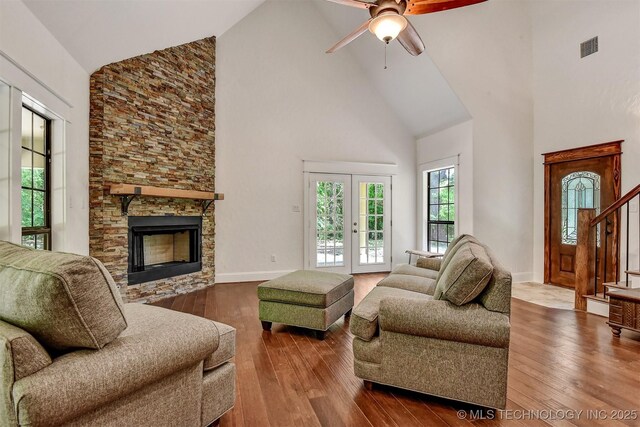 900 W Hardesty Rd, Caddo, OK 74729 - living room featuring high vaulted ceiling, a ceiling fan, wood-type flooring, a stone fireplace, and stairs