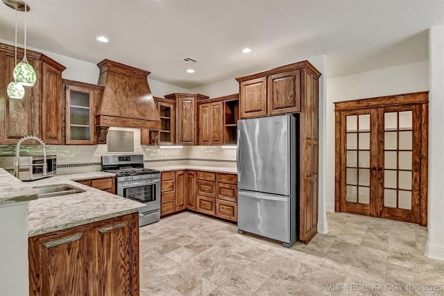 900 W Hardesty Rd, Caddo, OK 74729 - kitchen featuring appliances with stainless steel finishes, custom range hood, decorative backsplash, decorative light fixtures, and glass insert cabinets