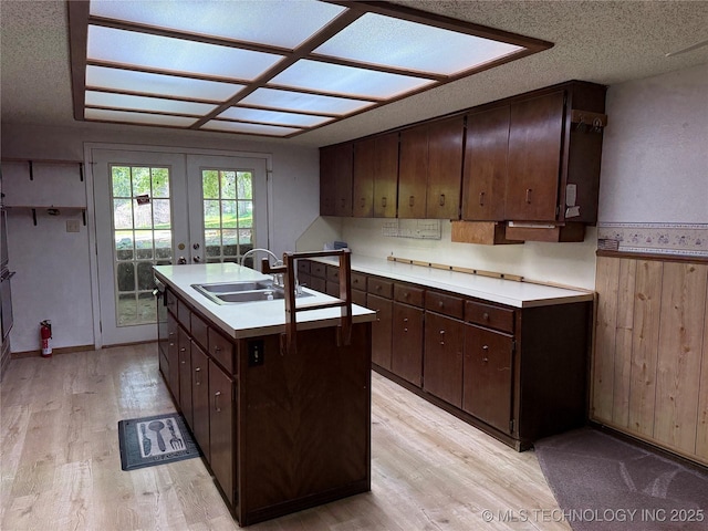 2099 S 80th St E, Muskogee, OK 74403 - kitchen with a sink, light wood-type flooring, an island with sink, dark brown cabinetry, and light countertops