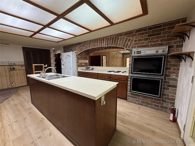 2099 S 80th St E, Muskogee, OK 74403 - kitchen with white appliances, a sink, light countertops, light wood finished floors, and brick wall