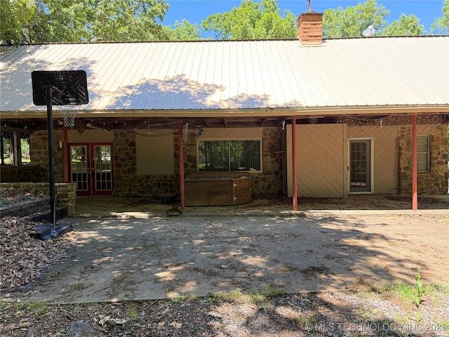 2099 S 80th St E, Muskogee, OK 74403 - view of front facade with french doors, stone siding, a chimney, and metal roof