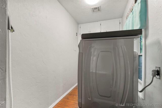 1732 N Little, Cushing, OK 74023 - washroom featuring wood finished floors, washer / clothes dryer, a textured wall, and a textured ceiling