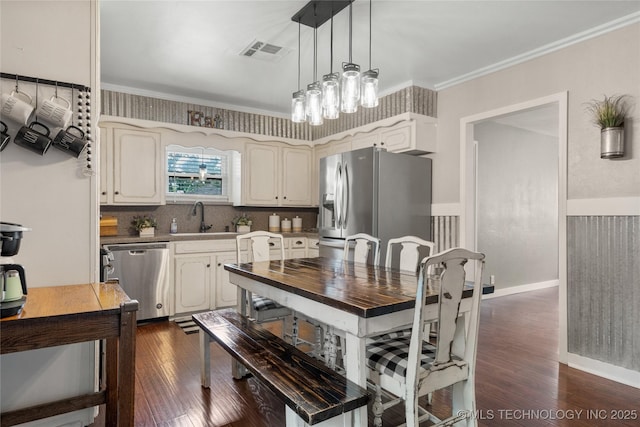 1732 N Little, Cushing, OK 74023 - kitchen with appliances with stainless steel finishes, dark wood-style floors, hanging light fixtures, backsplash, and ornamental molding