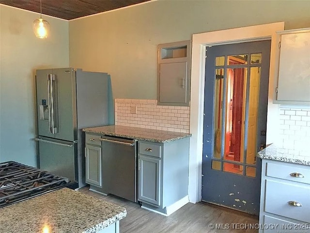 403 W Broadway, Marietta, OK 73448 - kitchen with light wood-style flooring, decorative backsplash, stainless steel appliances, light stone counters, and hanging light fixtures