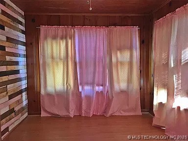 403 W Broadway, Marietta, OK 73448 - unfurnished room with wood walls, wood ceiling, wood finished floors, and plenty of natural light