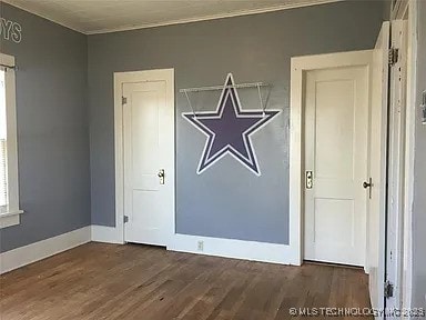403 W Broadway, Marietta, OK 73448 - unfurnished room featuring wood finished floors, crown molding, and baseboards
