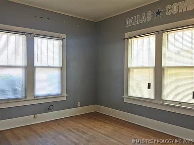 403 W Broadway, Marietta, OK 73448 - spare room with wood finished floors, plenty of natural light, and baseboards