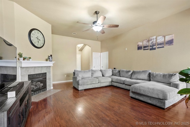 20225 E 44th St S, Broken Arrow, OK 74014 - living room featuring arched walkways, a tiled fireplace, ceiling fan, wood finished floors, and baseboards