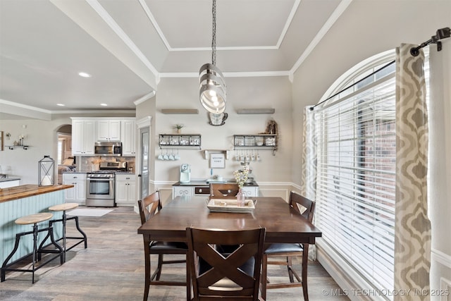 5720 E 144th St N, Collinsville, OK 74021 - dining area featuring healthy amount of natural light, arched walkways, wood finished floors, and crown molding