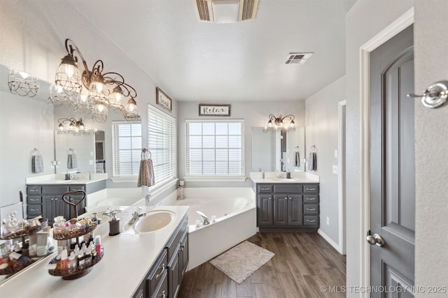 5720 E 144th St N, Collinsville, OK 74021 - bathroom with a chandelier, wood finished floors, a bath, and two vanities