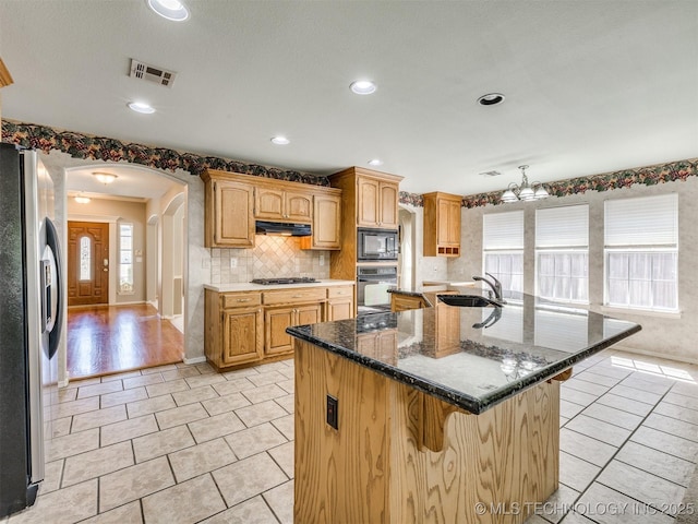 4708 W Indianola St, Broken Arrow, OK 74012 - kitchen with freestanding refrigerator, built in microwave, black oven, under cabinet range hood, and a kitchen bar