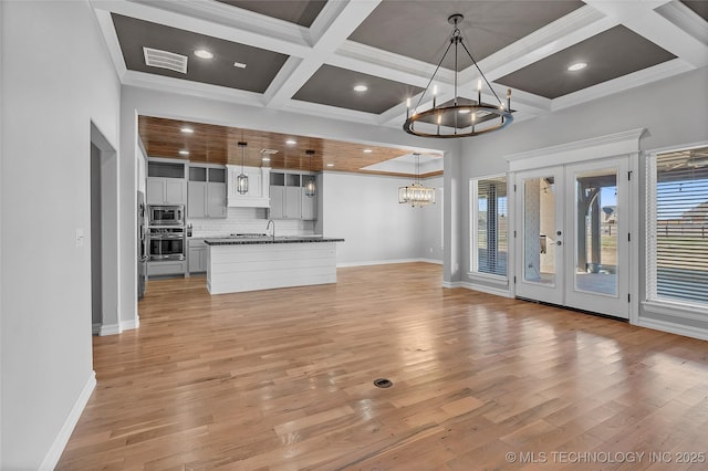 4922 S 81st W Ave, Tulsa, OK 74107 - unfurnished living room with a chandelier, light wood-style flooring, plenty of natural light, coffered ceiling, and beam ceiling