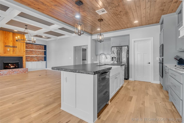 4922 S 81st W Ave, Tulsa, OK 74107 - kitchen featuring stainless steel appliances, a sink, light wood-style floors, a chandelier, and coffered ceiling