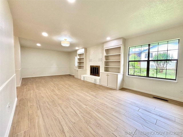 1903 Swan Ln, Mcalester, OK 74501 - unfurnished living room with baseboards, light wood-style floors, a brick fireplace, recessed lighting, and a textured ceiling