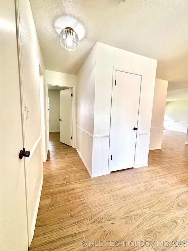 1903 Swan Ln, Mcalester, OK 74501 - hall featuring a textured ceiling, light wood-style floors, and baseboards