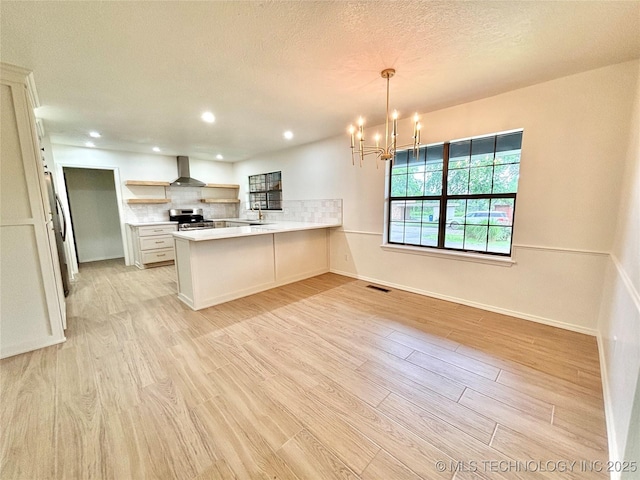 1903 Swan Ln, Mcalester, OK 74501 - kitchen with stainless steel stove, wall chimney range hood, a peninsula, light wood finished floors, and open shelves