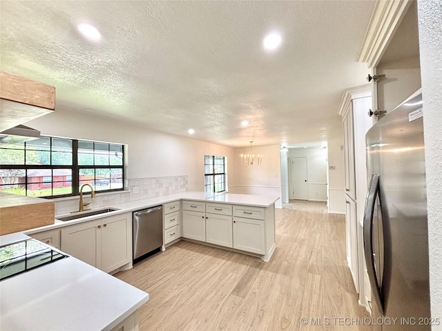 1903 Swan Ln, Mcalester, OK 74501 - kitchen with stainless steel appliances, a sink, a peninsula, a chandelier, and light countertops