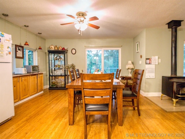 5404 Ranch Rd, Kingston, OK 73439 - dining room with a wood stove, a ceiling fan, light wood-style flooring, and plenty of natural light