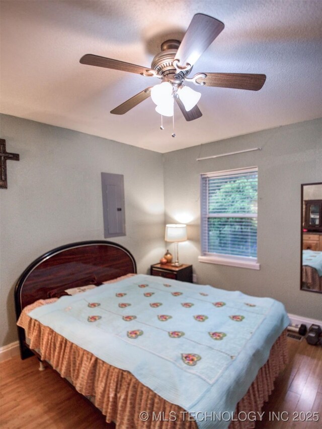 5404 Ranch Rd, Kingston, OK 73439 - bedroom featuring electric panel, wood finished floors, baseboards, and ceiling fan