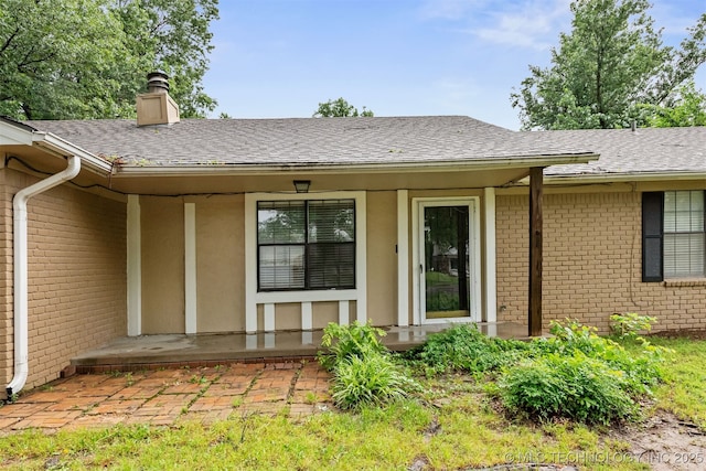 202 NE B St NE, Inola, OK 74036 - doorway to property with brick siding, a shingled roof, and a chimney