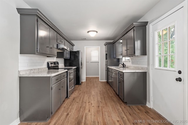 202 NE B St NE, Inola, OK 74036 - kitchen featuring appliances with stainless steel finishes, under cabinet range hood, baseboards, and backsplash
