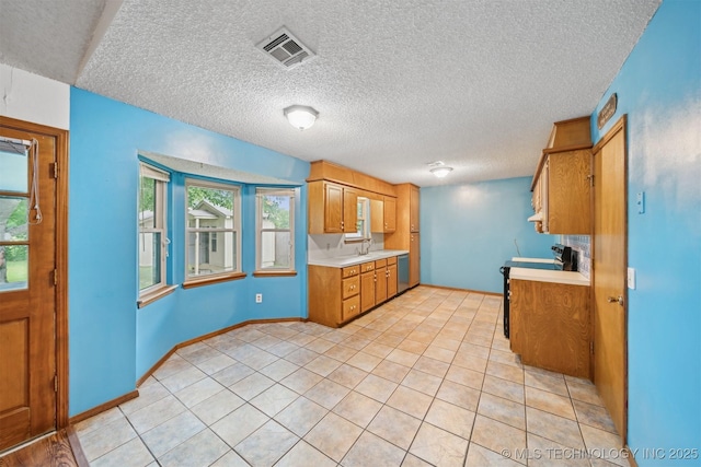 2910 S Main St, Sapulpa, OK 74066 - kitchen featuring light countertops, dishwasher, a textured ceiling, brown cabinetry, and light tile patterned flooring