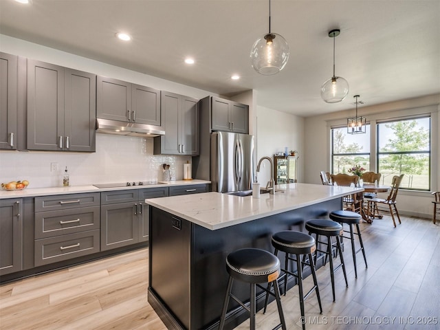 8859 N 50th W Ave, Sperry, OK 74073 - kitchen with freestanding refrigerator, under cabinet range hood, gray cabinetry, black electric stovetop, and a breakfast bar