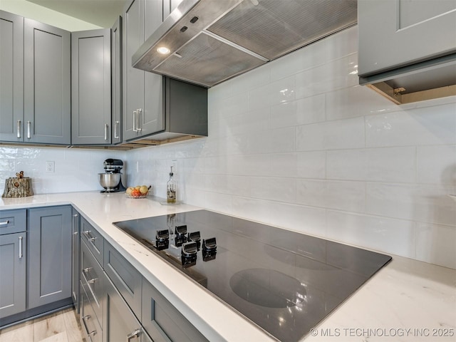 8859 N 50th W Ave, Sperry, OK 74073 - kitchen with wall chimney range hood, black electric stovetop, gray cabinetry, and backsplash