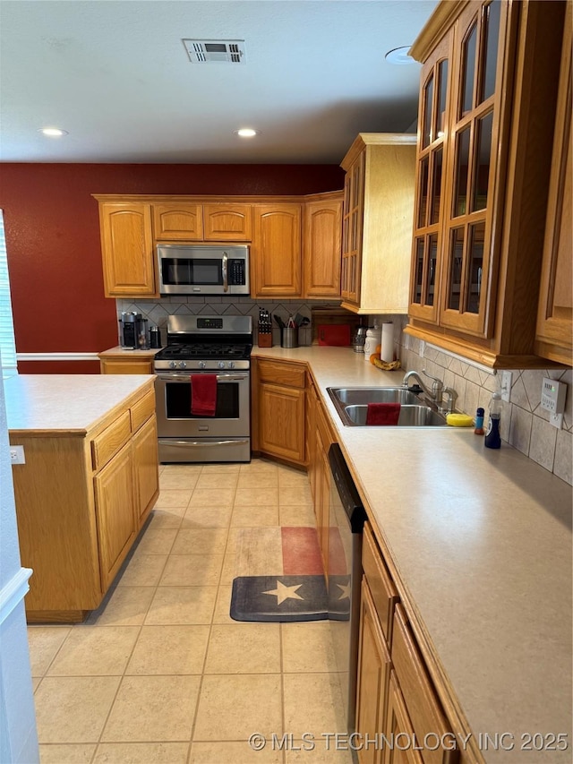 9701 N 98th E Ave, Owasso, OK 74055 - kitchen featuring stainless steel appliances, a sink, decorative backsplash, light countertops, and glass insert cabinets