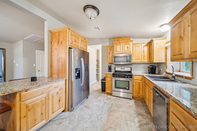 6529 S 159th Ave W, Sapulpa, OK 74066 - kitchen featuring appliances with stainless steel finishes, a sink, light stone counters, a peninsula, and light brown cabinetry
