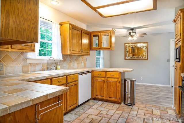 4605 Skylane Dr, Sand Springs, OK 74063 - kitchen featuring dishwasher, a sink, a peninsula, and brown cabinetry