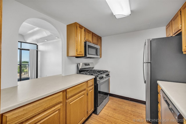 410 W 7th St Unit 1122, Tulsa, OK 74119 - kitchen with appliances with stainless steel finishes, arched walkways, light wood-style floors, light countertops, and baseboards