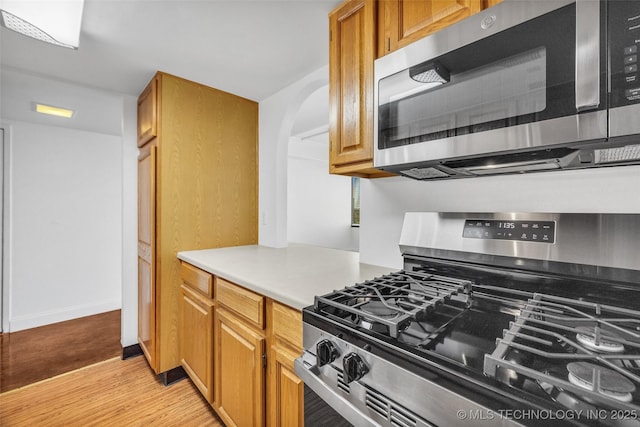 410 W 7th St Unit 1122, Tulsa, OK 74119 - kitchen featuring stainless steel appliances, light wood-style flooring, light countertops, arched walkways, and baseboards