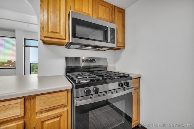 410 W 7th St Unit 1122, Tulsa, OK 74119 - kitchen featuring appliances with stainless steel finishes, light countertops, arched walkways, and brown cabinets