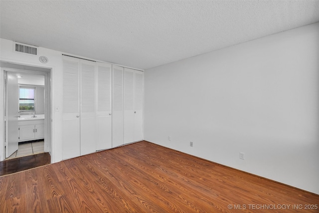 410 W 7th St Unit 1122, Tulsa, OK 74119 - unfurnished bedroom with a textured ceiling, wood finished floors, and a closet