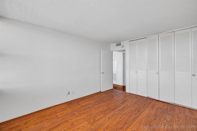 410 W 7th St Unit 1122, Tulsa, OK 74119 - unfurnished bedroom with wood finished floors, a textured ceiling, and a closet