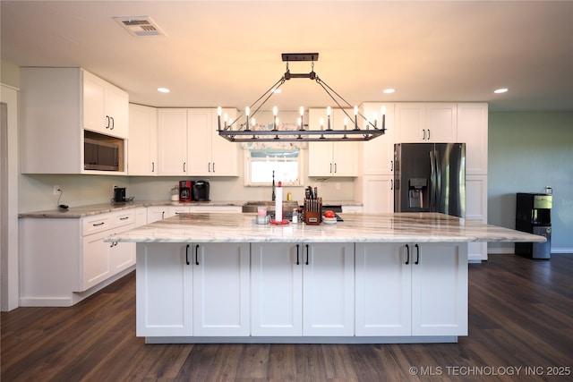 8845 Chestnut Rd, Henryetta, OK 74437 - kitchen featuring appliances with stainless steel finishes, a chandelier, white cabinets, a spacious island, and light stone countertops
