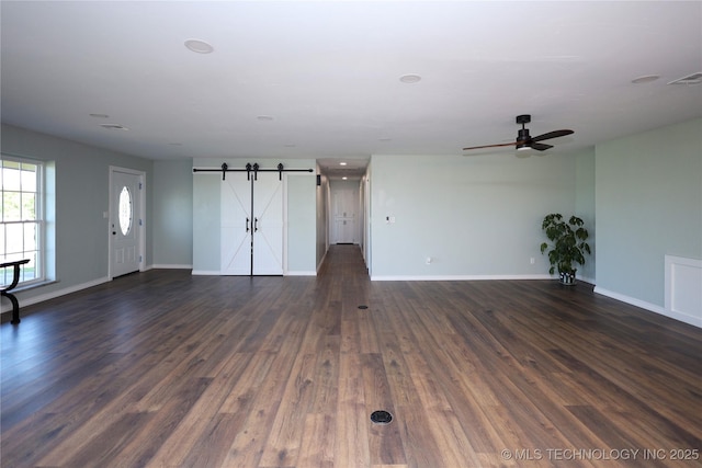 8845 Chestnut Rd, Henryetta, OK 74437 - unfurnished living room featuring baseboards, a barn door, dark wood-style flooring, and a ceiling fan