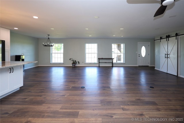 8845 Chestnut Rd, Henryetta, OK 74437 - unfurnished living room featuring a barn door, recessed lighting, baseboards, dark wood finished floors, and ceiling fan
