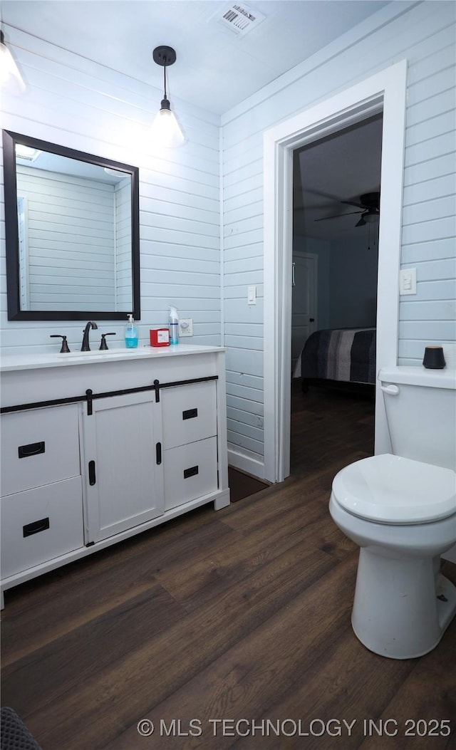 8845 Chestnut Rd, Henryetta, OK 74437 - bathroom with vanity, wood finished floors, toilet, and wooden walls