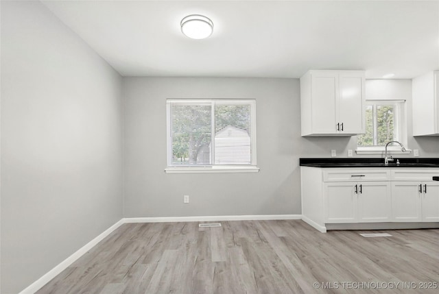 11607 E 24th St, Tulsa, OK 74129 - kitchen featuring light wood-style floors, baseboards, white cabinets, and dark countertops