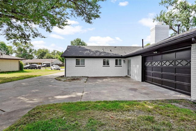 11607 E 24th St, Tulsa, OK 74129 - back of house featuring brick siding, a chimney, a shingled roof, and an attached garage
