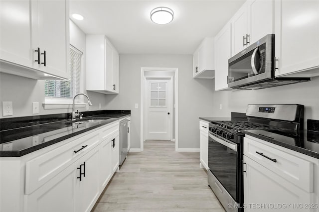 11607 E 24th St, Tulsa, OK 74129 - kitchen featuring appliances with stainless steel finishes, a sink, white cabinetry, light wood-type flooring, and baseboards