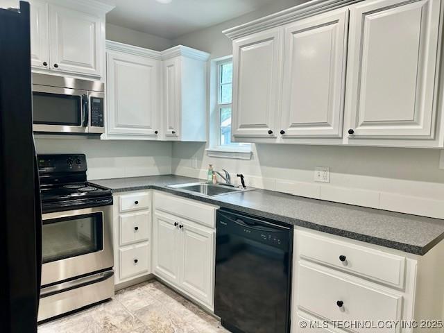 16 Q St SW, Ardmore, OK 73401 - kitchen featuring black appliances, a sink, dark countertops, and white cabinets