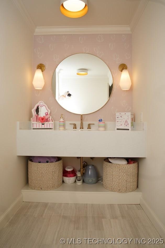 2233 E 32nd St, Tulsa, OK 74105 - bathroom featuring crown molding, wallpapered walls, a sink, baseboards, and wood finished floors
