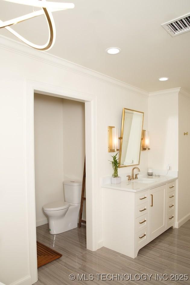 2233 E 32nd St, Tulsa, OK 74105 - bathroom with vanity, toilet, ornamental molding, baseboards, and recessed lighting